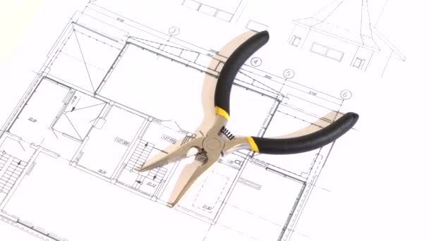 Gray and yellow round-nose pliers on building plan, scheme, rotation — Stock Video