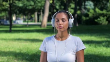Kız parkta yoga yaparken ve kulaklıklar müzik dinlemek. Güneşli gün