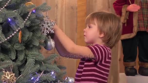 Söt liten tjej dekorera julgran, trä bakgrund — Stockvideo