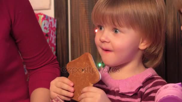 Маленькая девочка ест рождественский торт, торт в форме рождественских деревьев — стоковое видео
