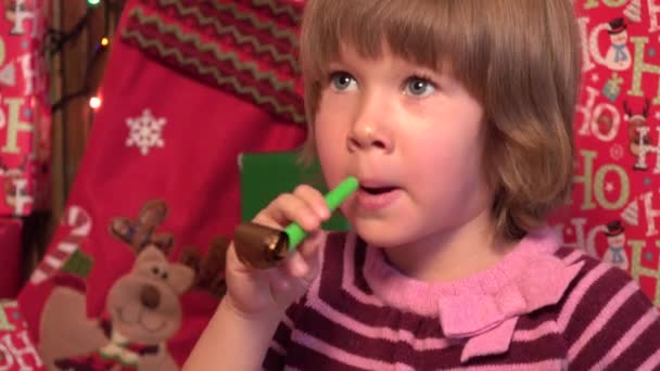 Little girl laughing on new years eve, blowing horn — Stock Video