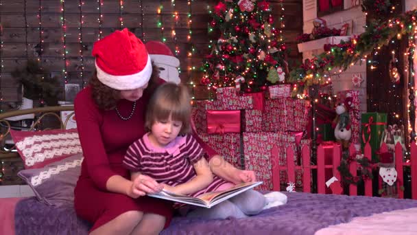 Moeder en haar dochter lezen bed Kerstmis achtergrond — Stockvideo