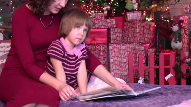 Μαμά δείχνει κόρη εικόνες σε ένα βιβλίο, Χριστούγεννα διακοσμήσεις — Αρχείο Βίντεο