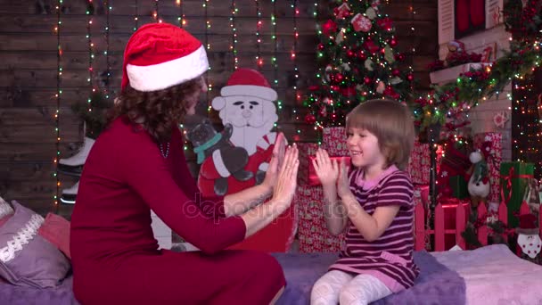 Moeder met haar kind dochter gekleed in mooie mode rode jurk vieren in de buurt van de kerstboom — Stockvideo