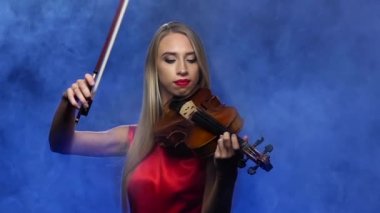 Kız sarışın keman çalıyor. Dumanlı arka plan. Ağır çekim