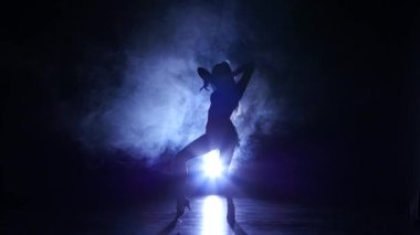Studio, rumba dans kadın silueti. Koyu arka plan, mavi arka plan ışığı