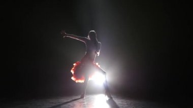 Karanlık bir arka planda, duman, beyaz arka ışığı ile stüdyoda rumba dans güzel kız
