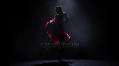 Dumanlı karanlık bir arka plan üzerinde dans eden kız siluet. Ağır çekim