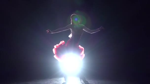 Chica bailando latino sobre un fondo oscuro con iluminador de luz. Movimiento lento — Vídeos de Stock