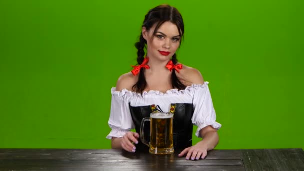 Meisje met de rode lippen en een Beierse kostuum serveert bier. Groen scherm — Stockvideo