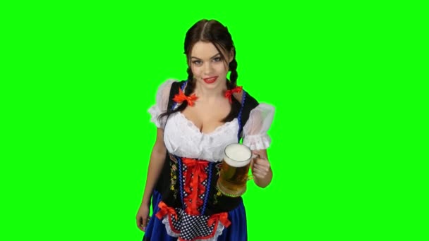 Девушка в баварском костюме празднует Октоберфест, пьет пиво и манит. Зеленый экран — стоковое видео