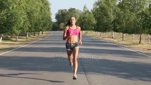 La deportista corre en medio de la carretera. Movimiento lento — Vídeo de stock