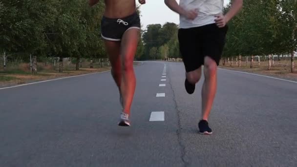 Sportsman och idrottskvinna körs på mitten av vägen — Stockvideo