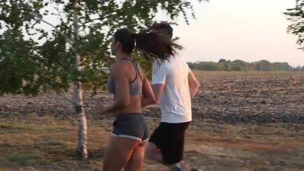 El par de deportistas corriendo al atardecer. Movimiento lento — Vídeo de stock