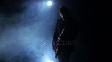 Müzisyen gitar dizeleri koparmak. Duman. Karanlık stüdyo