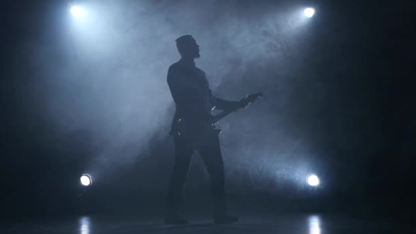 スローモーションでギタリストは、エレク トリック ギターを果たしています。背景を煙します。スタジオ — ストック動画