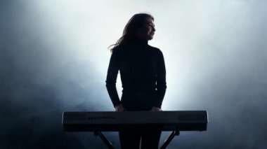 Hızlı müzik üzerinde bir elektronik piyano çalan kız. Duman. Stüdyo