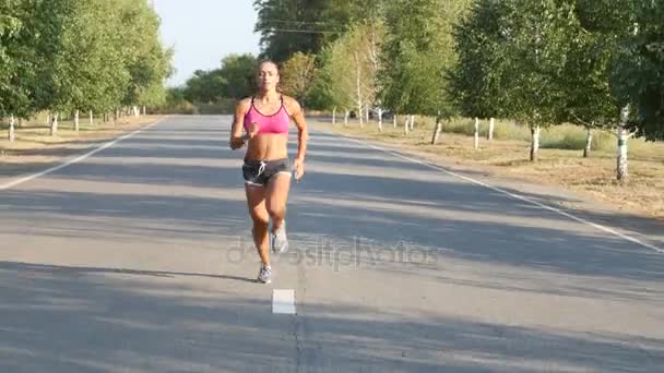 Красивая спортсменка бегает по проселочной дороге. Обучение на открытом воздухе — стоковое видео