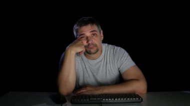Adam bir bilgisayar ekranına bakarak kayıtsızlık ile