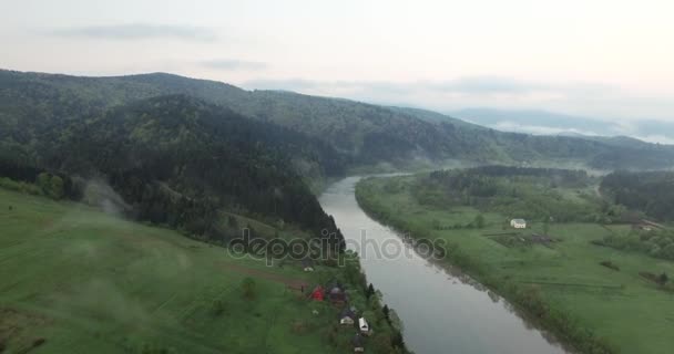 Rzeką u podnóża niskie zalesione wzgórza. Widok z lotu ptaka — Wideo stockowe