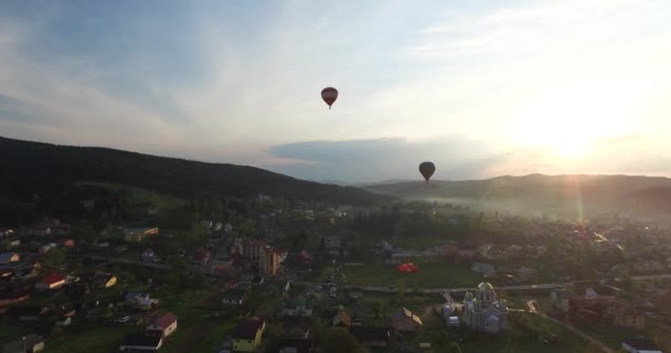 Två ballongen flyger över staden i solen — Stockvideo