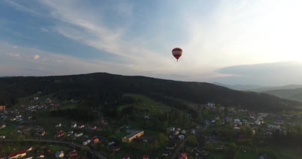 Ballongen flyger ovanför en liten stad närmare till skogen — Stockvideo