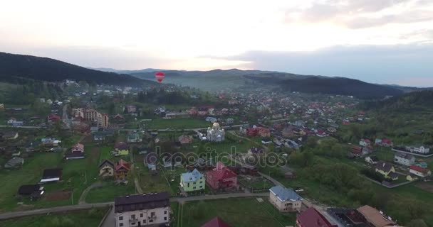 Μπαλόνι προσγειώνεται στο πράσινο γκαζόν σε μια μικρή πόλη — Αρχείο Βίντεο
