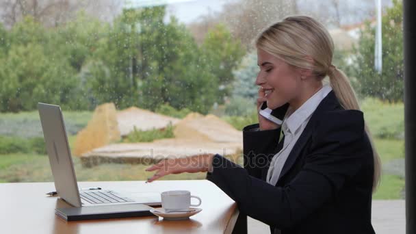 Usmívající se žena mluví po telefonu a práci na notebooku — Stock video