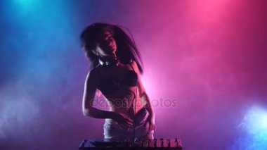 Kız dj el duman onun pembe mavi ışıkları arkasında bir dj standı iplik