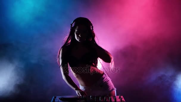 Girl DJ dancing develop her hair behind her multicolored lights and smoke. Silhouette — Stock Video