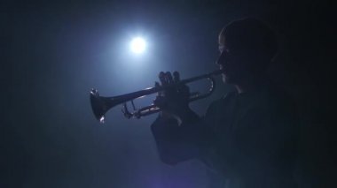 Trompetçi Nefesli/Üflemeli Saz sakin melodi çalar. Stüdyo duman