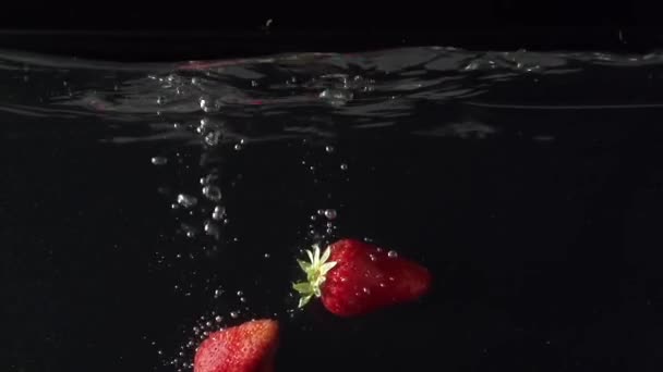 Twee strawberryes laten vallen in water in slowmotion — Stockvideo