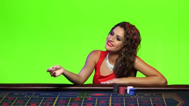 Сексуальна дівчина грає з чипом, сидячи за столом покеру — стокове відео