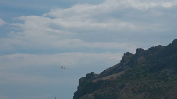 Bergen på himmel bakgrund och fallskärm flugor — Stockvideo