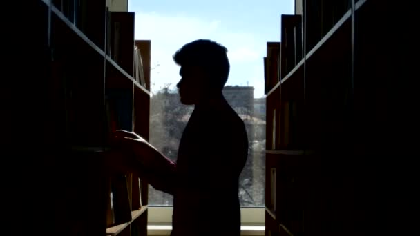 Silueta mladý student čtení knihy v knihovně