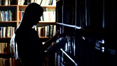 oldukça genç üniversite öğrencisi bir Kitaplığı'nda, bir kitap seçer. Geri ışık kapatın