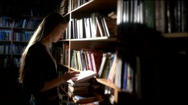 oldukça genç üniversite öğrencisi bir Kitaplığı'nda, bir kitap seçer. Yakın çekim