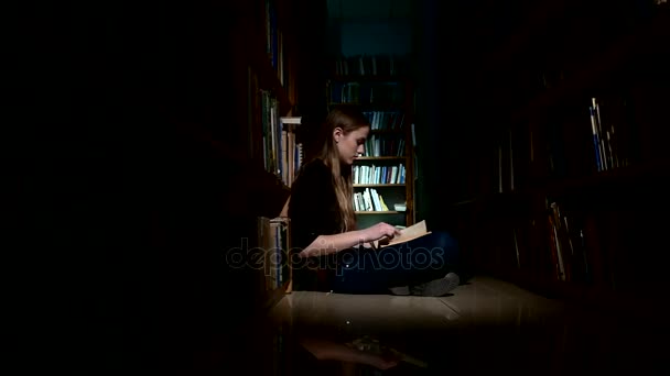 Student tjej sitter på golvet och läsa bok i biblioteket — Stockvideo