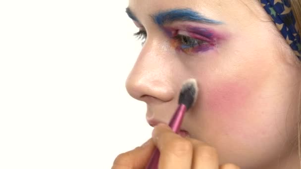 エキゾチックな作る目メイクの女性が、アイシャドウを適用する 1 つ、青い眉、ほお紅、上向きに、近くには、白 — ストック動画