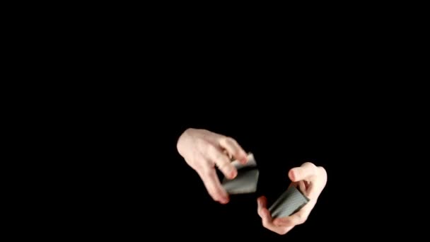 Чарівник перемішує карти незвичайним чином на чорному — стокове відео