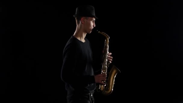 Blues w wydajności młody muzyk saksofonista. Czarne tło studio — Wideo stockowe
