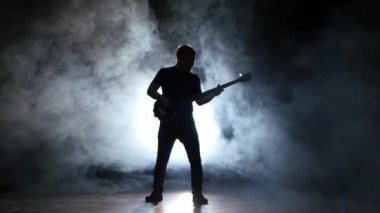 Bas gitarist aşağı enstrüman üzerinde oynarken diz çöker