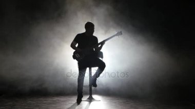 Gitarist yüksek sandalyede oturan bir acelesiz melodi çalıyor