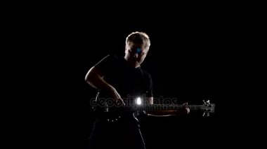 Aşağı dizlerinin üstüne bas gitarist koparmak dizeleri. Siyah arka plan