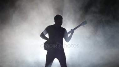 Dumanlı bir stüdyoda müzisyen adam ustaca bas gitar çalan