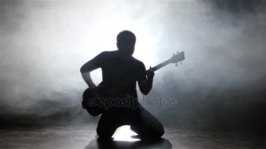 Dizlerinin üzerinde gitar çalmak basçı genç adam. Ağır çekim