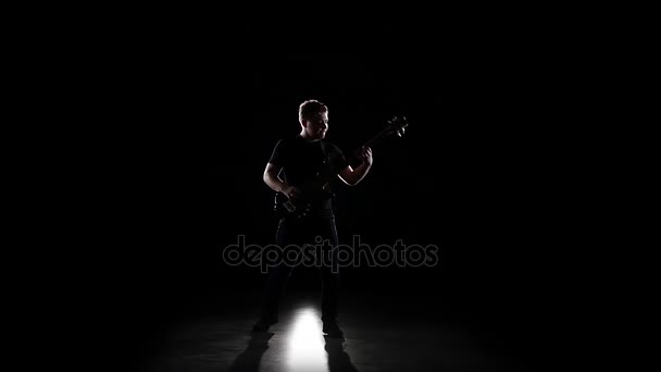 Бас-гітарист грає мелодії на колінах. Повільний рух — стокове відео