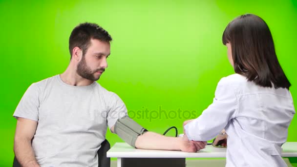 Mann misst den Druck einer niedlichen Krankenschwester. Green Screen — Stockvideo