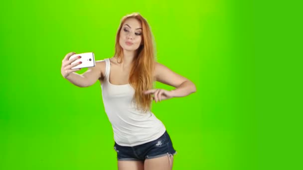 Selfie fotos en el teléfono móvil, plantea modelo chica pelirroja. Estudio — Vídeo de stock