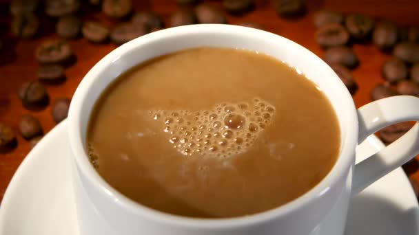 У білій чашці з гарячою чорною кавою додається молоко. крупним планом — стокове відео